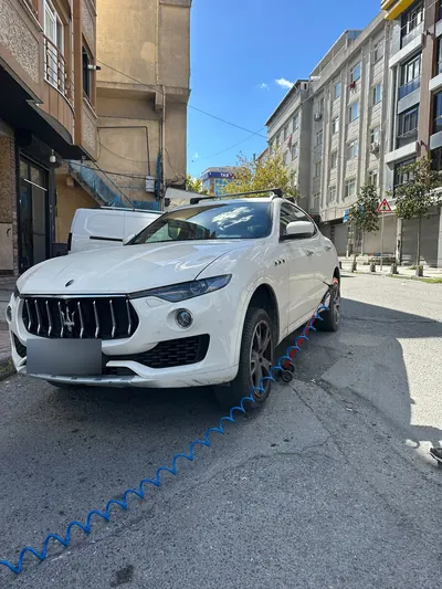 Gündüz sokakta beyaz SUV aracın ön lastiğine hava hortumuyla müdahale