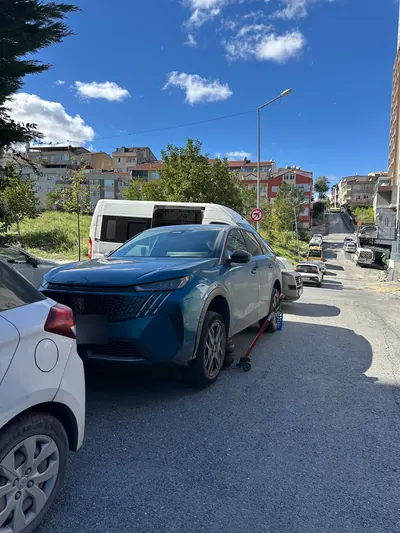 Yokuşlu sokakta mavi SUV aracın lastik değişimi
