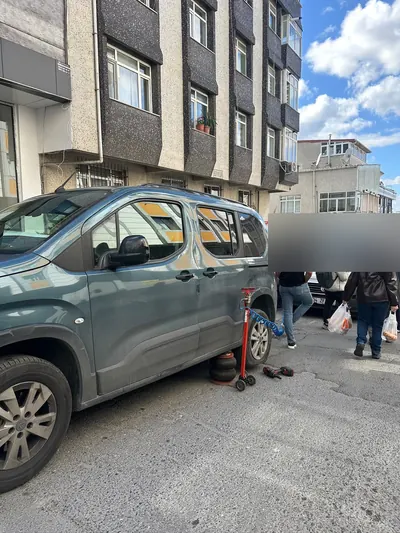 Sokak arasında hafif ticari aracın arka lastiğinin krikoyla kaldırılması