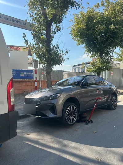 Gündüz sokakta sedan aracın ön lastiğinin krikoyla kaldırılması