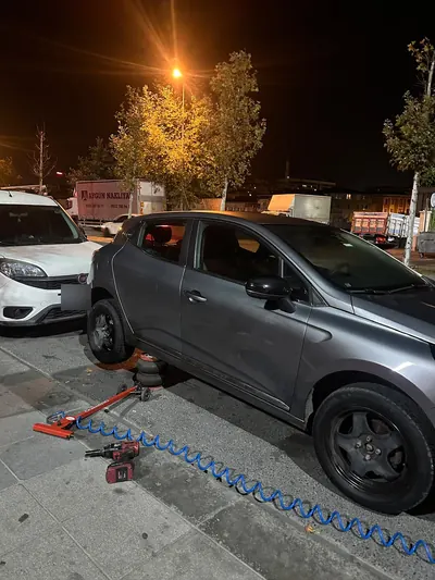 Gece otoparkta hatchback aracın arka lastiğinin krikoyla değişimi