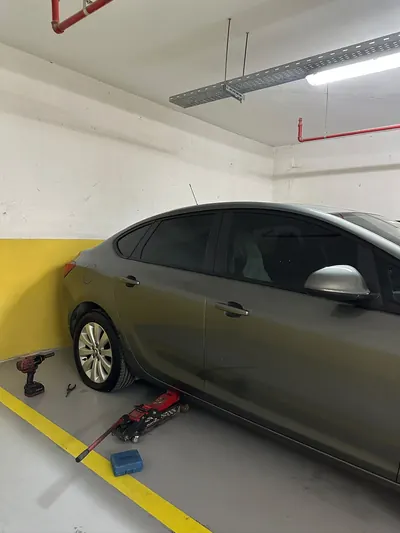 Kapalı otoparkta sedan aracın arka lastiğine kriko ile müdahale