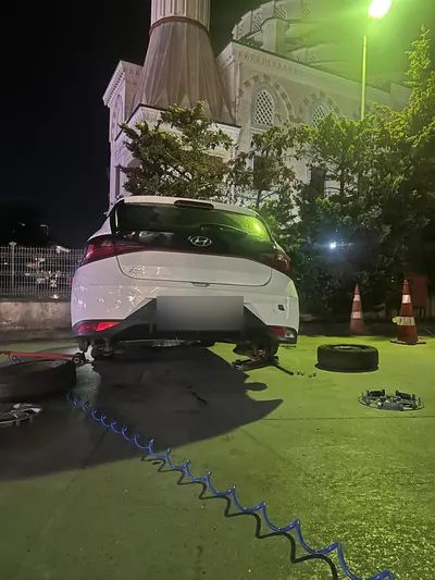 Gece otoparkta hatchback aracın arka tekerlerinin sökülüp değiştirilmesi