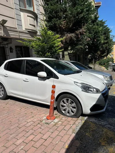 Kaldırım kenarında inik ön lastiğiyle bekleyen hatchback araç
